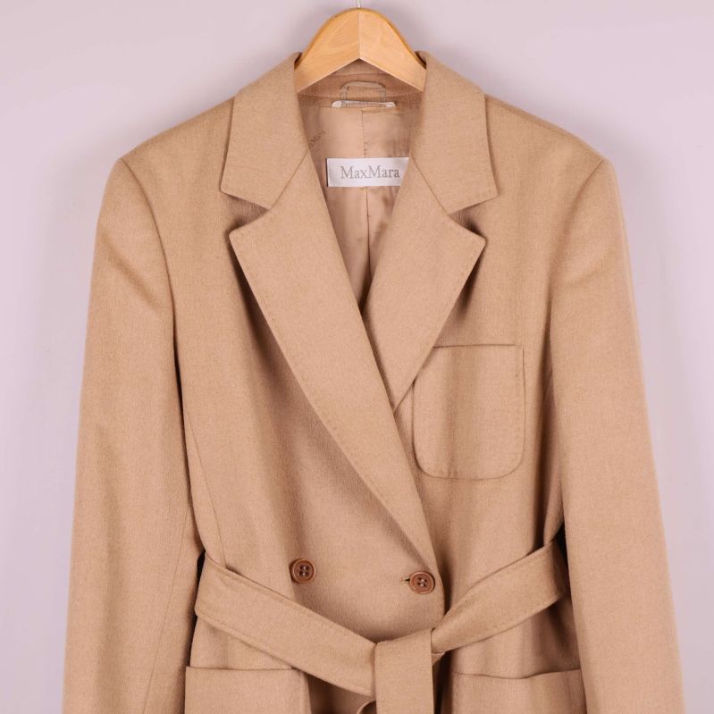 Överkroppsdel på beige kavaj med knappar och ficka