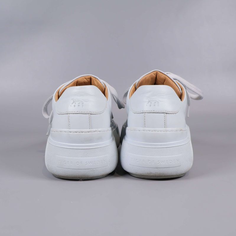 Baksidan av vita sneakers visar präglad logga