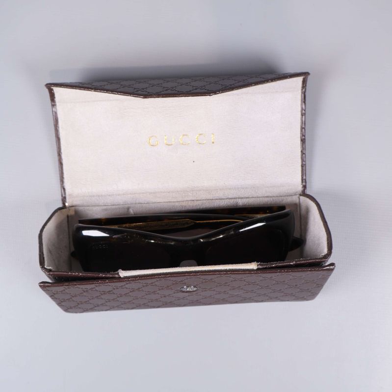 Öppen glasögonask med solglasögon inuti, logotyp synlig