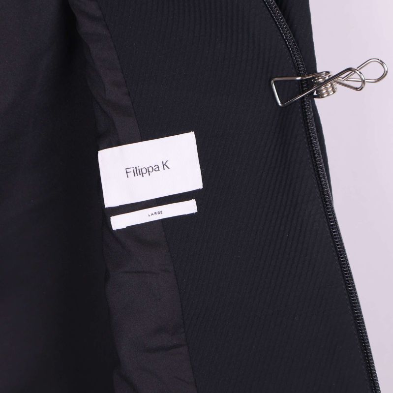 Etikett med Filippa K och storlek large i svart jacka