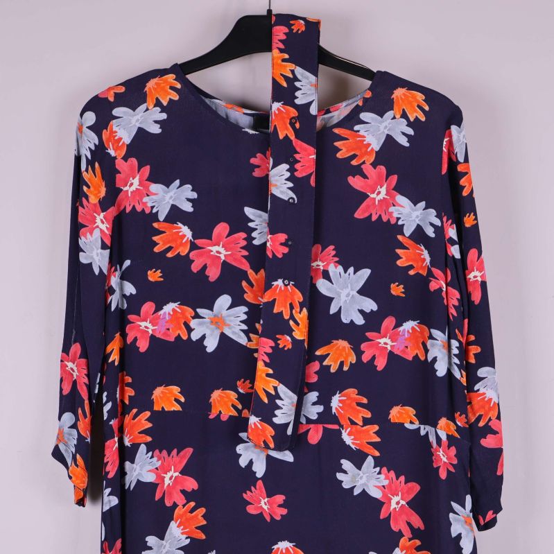 Övre del av klänning visar knytband och blommönster