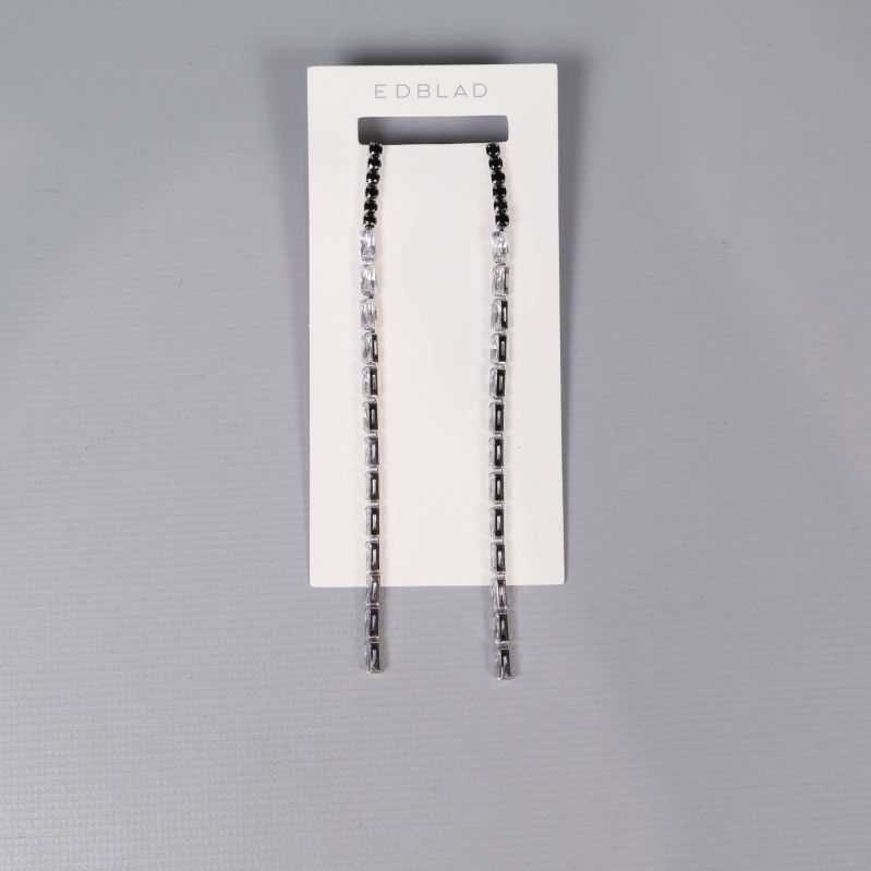 Långa örhängen med svarta och klara stenar på vit display