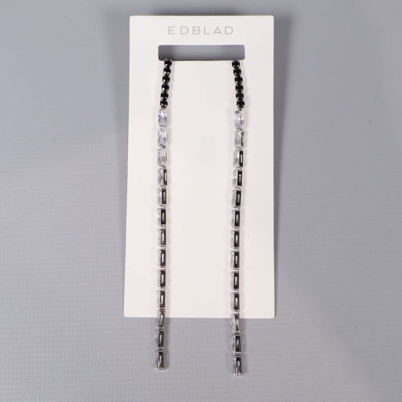 Närbild på örhängen med kontrast av svarta och klara rektangulära stenar