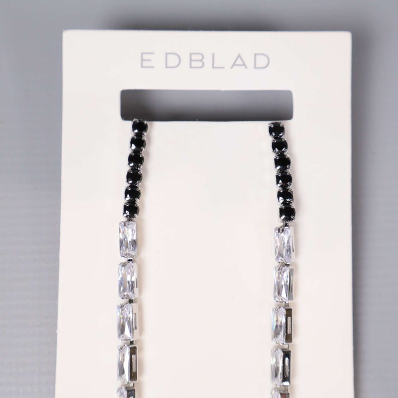 Örhängenas övre del med svart och klar pärlrad visas närmare