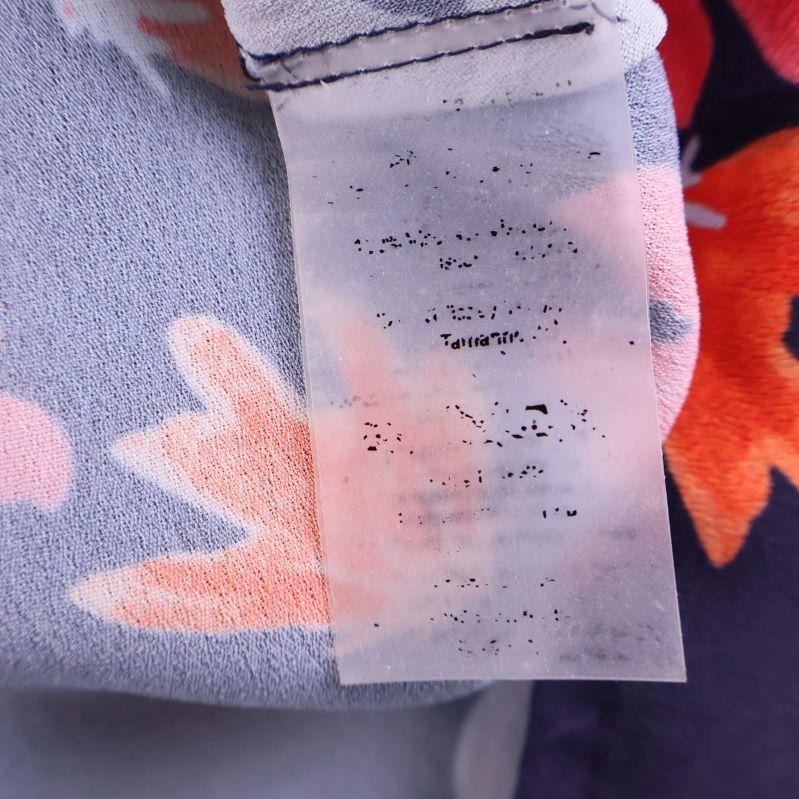 Materiallapp på blommig klänning, text svårläst