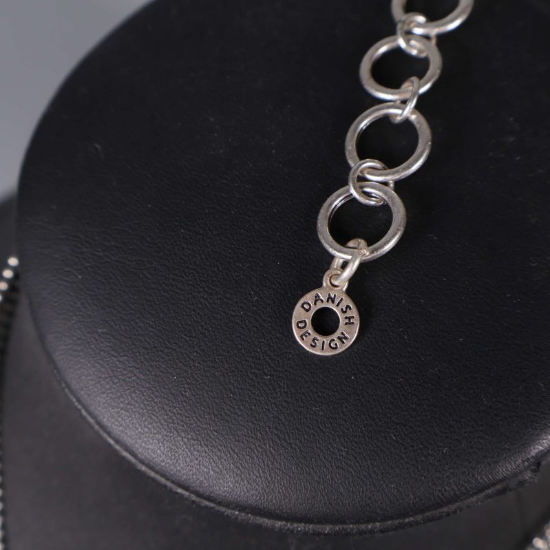 Närbild av märkning Danish Design på halsbandskedjan