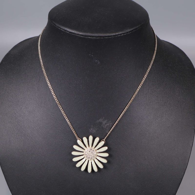 Närbild på halsband med detaljrik blomma i centrum