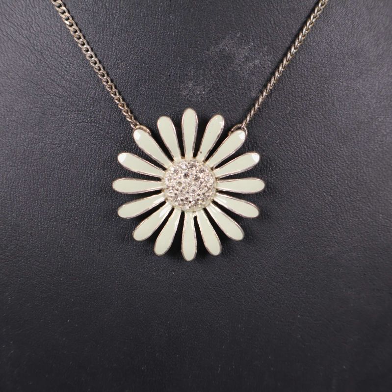 Hängsmycke utformat som en blomma med stenar i mitten