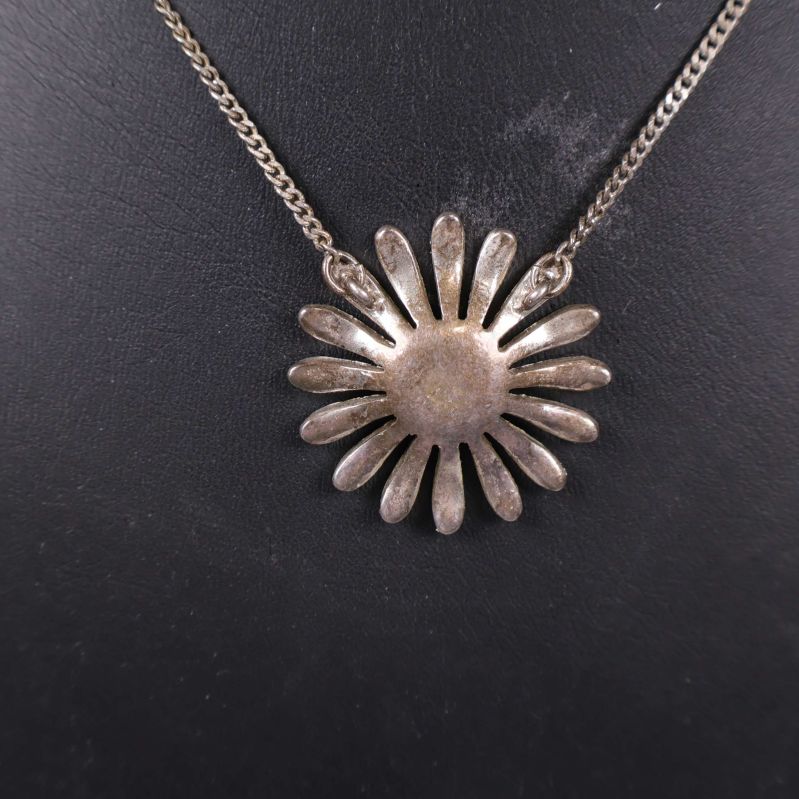 Baksidan av det blomformade hängsmycket visas tydligt