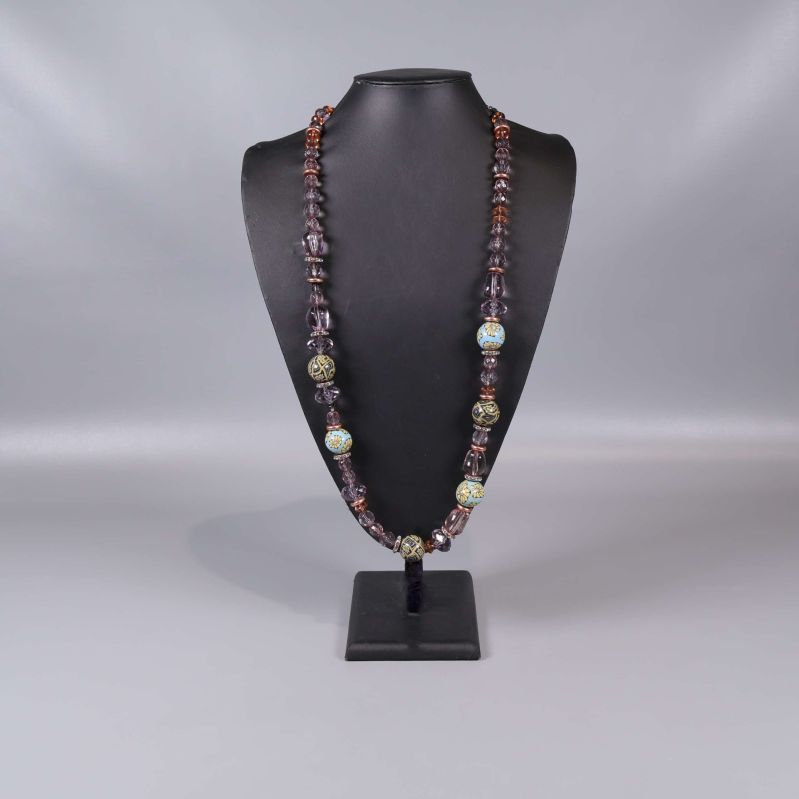 Långt halsband med blå och lila pärlor på bystställ