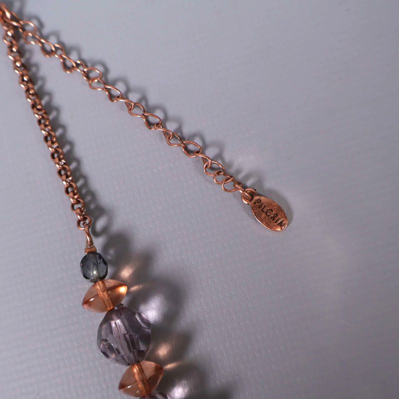 Närbild på halsbandets kedja och litet metallmärke