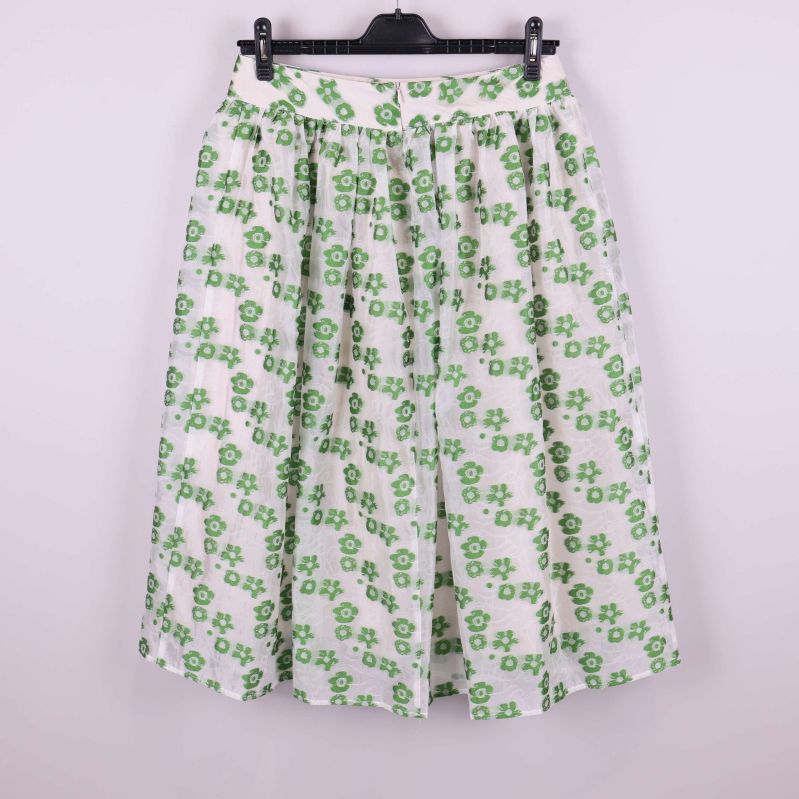 Vit kjol med gröna blommor bakifrån på galge