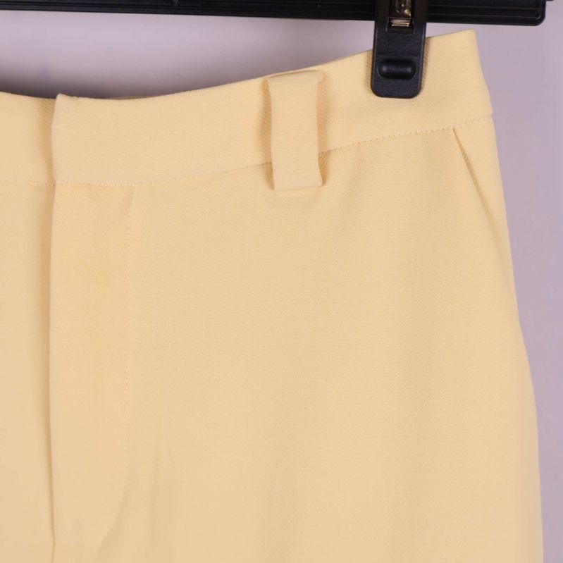 Detaljbild på midja och bälteshällor i ljusgult tyg