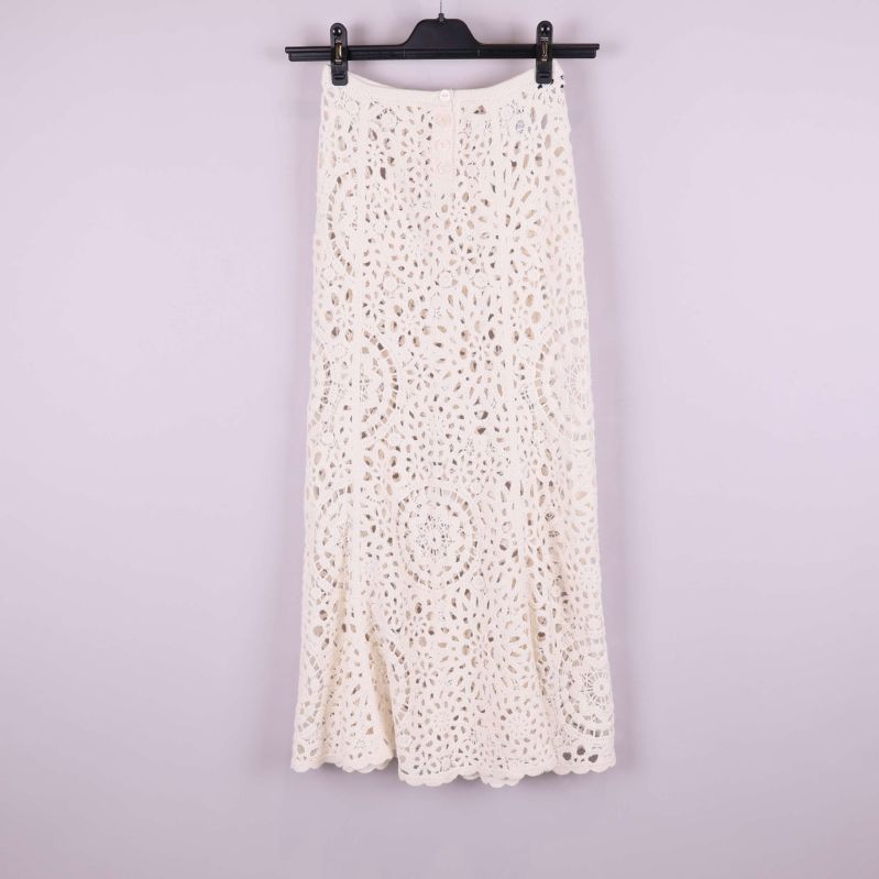 Framsida av lång krämvit virkad kjol på galge