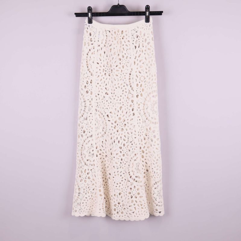 Baksida av lång krämvit virkad kjol på galge