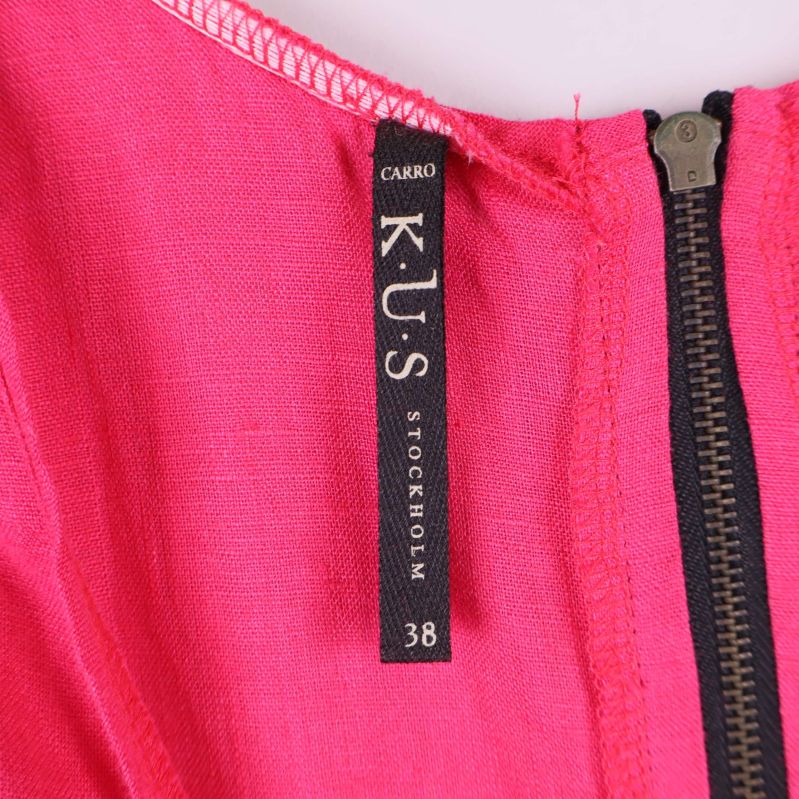 Närbild av klänningsetikett med varumärke K.U.S och storlek 38