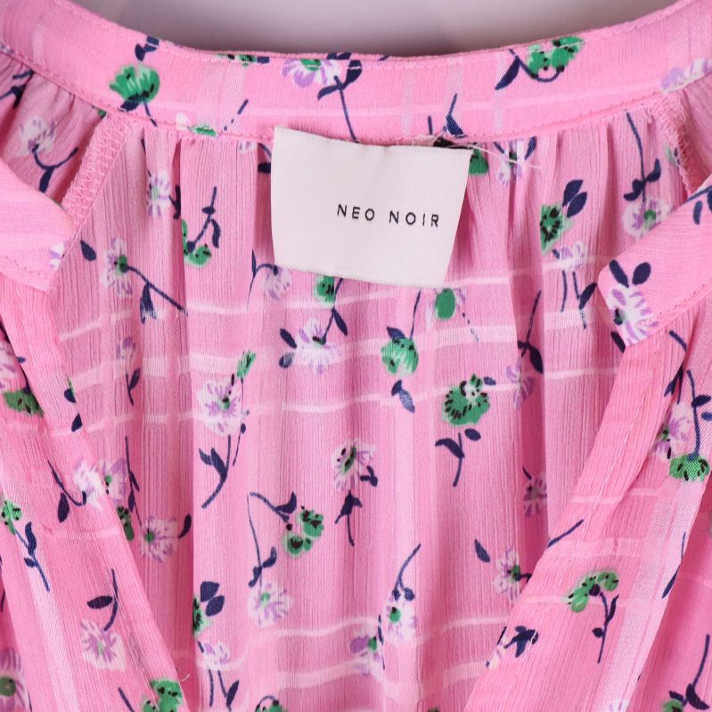 Närbild på Neo Noir-märke och blommigt tyg