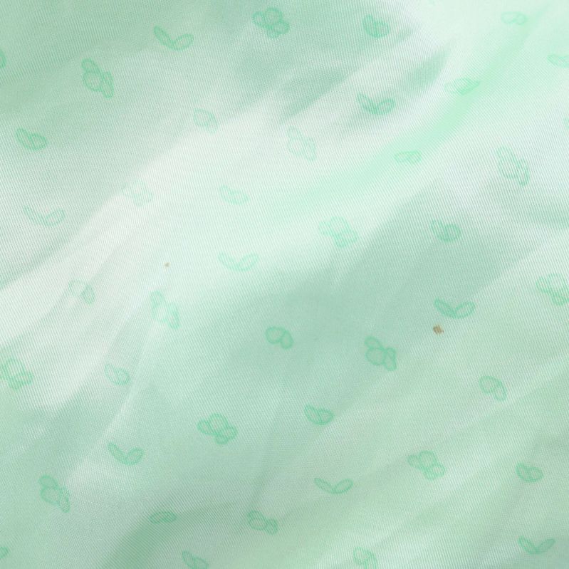 Textil närbild med små mintgröna mönstertryck