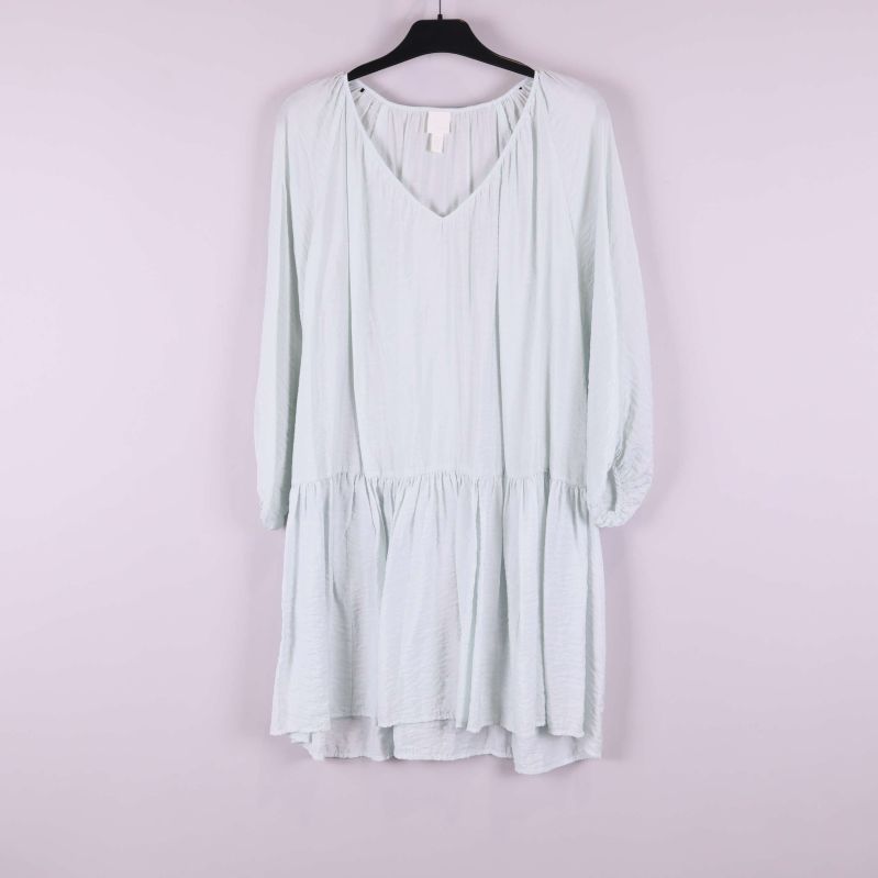 Ljus klänning med v-ringning och volangkant framifrån