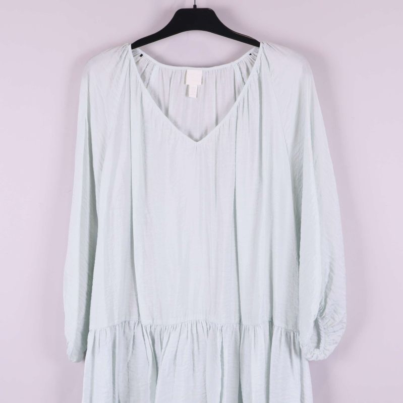 V-ringning och axelparti på ljus klänning tydligt