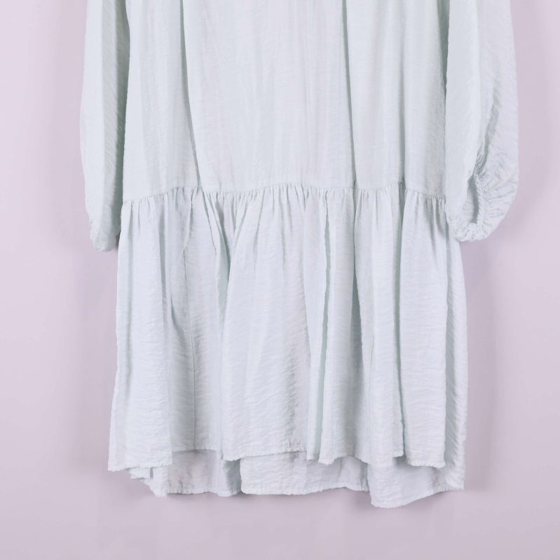 Volangkantad nederdel på ljus klänning i närbild