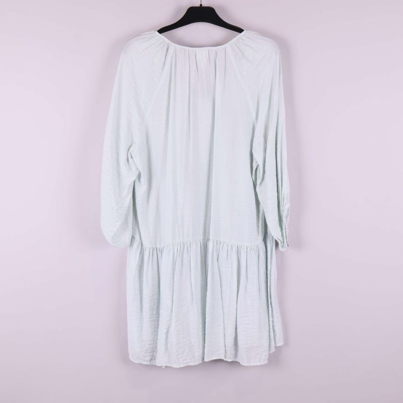 Ljus klänning med vidd och volangkant bakifrån