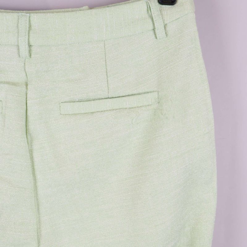 Närbild på ficka och tygstruktur på ljusgröna byxor