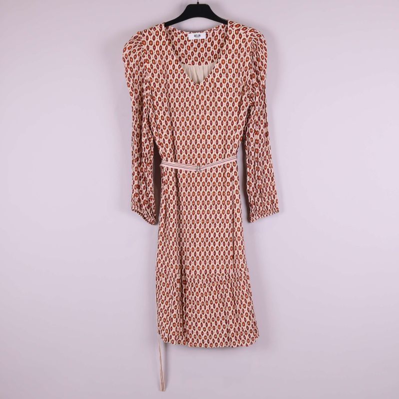 Framsidan av mönstrad klänning på galge med midjeband