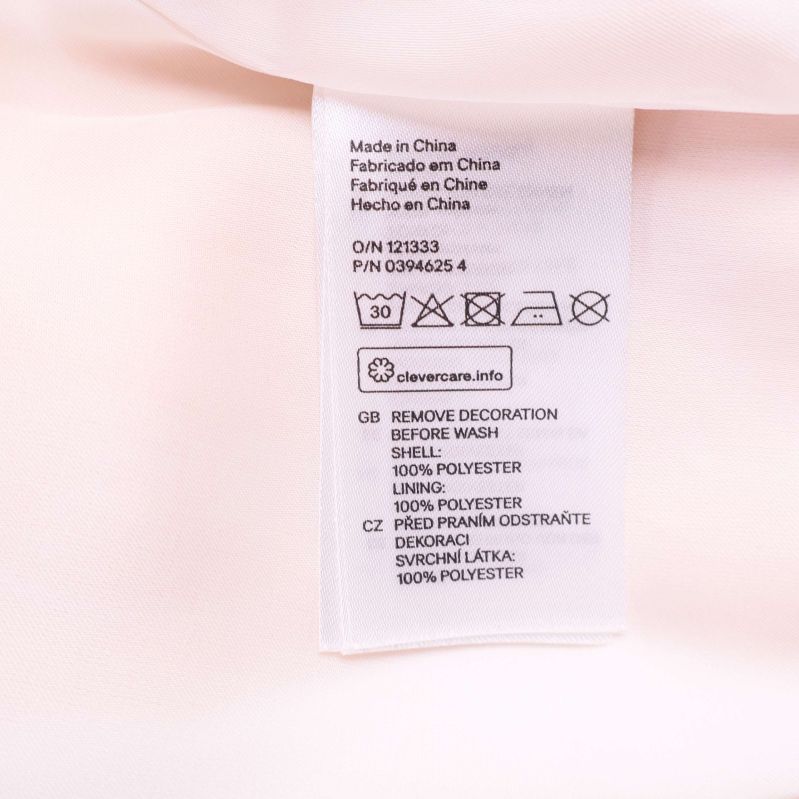 Materialetikett som visar 100% polyester för både skal och foder