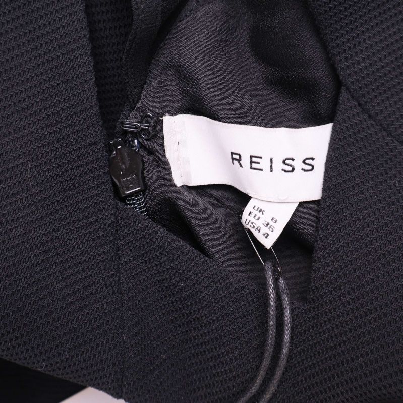 Vit etikett med Reiss-logotyp hängande från klänningen