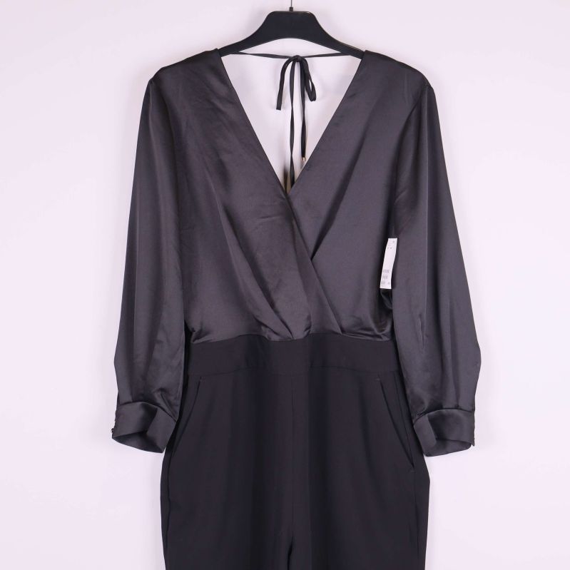 Närbild framtill på svart jumpsuit med insnitt och fickor