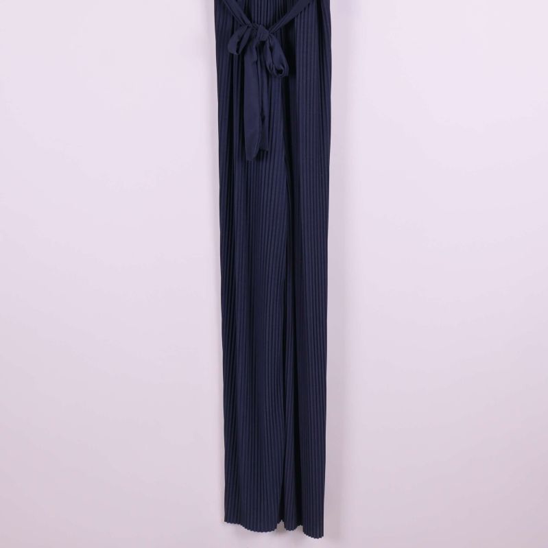 Plisserade långa ben på mörkblå jumpsuit i närbild