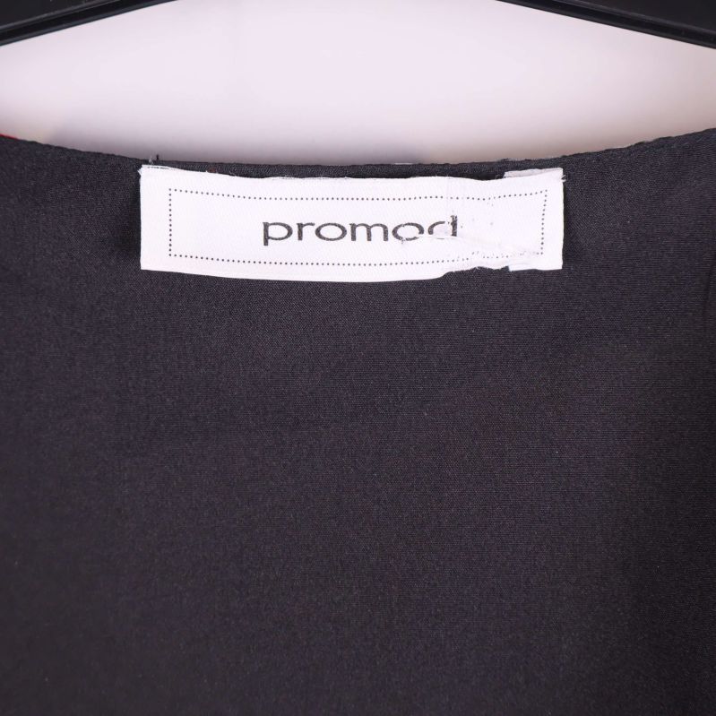 Närbild på vit promod-etikett mot svart foder