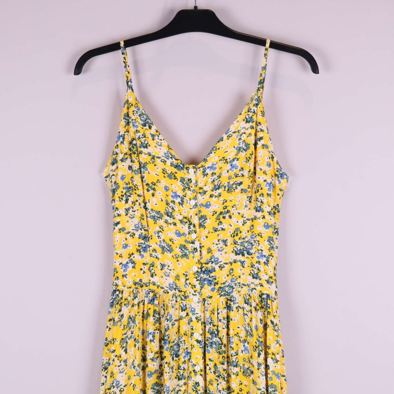 Överdel av gulblommig klänning, v-ringning och smala axelband i närbild