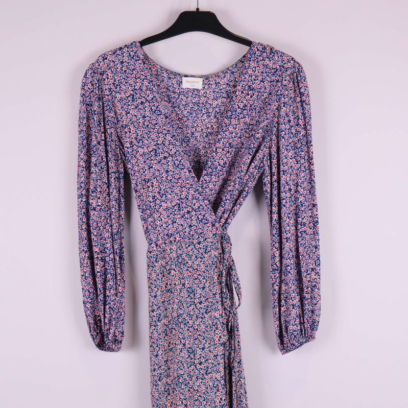 Överkroppsdetalj på blommig omlottklänning med lång ärm