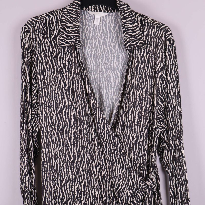 Detalj framtill på omlottklänningen med mönster och v-ringning