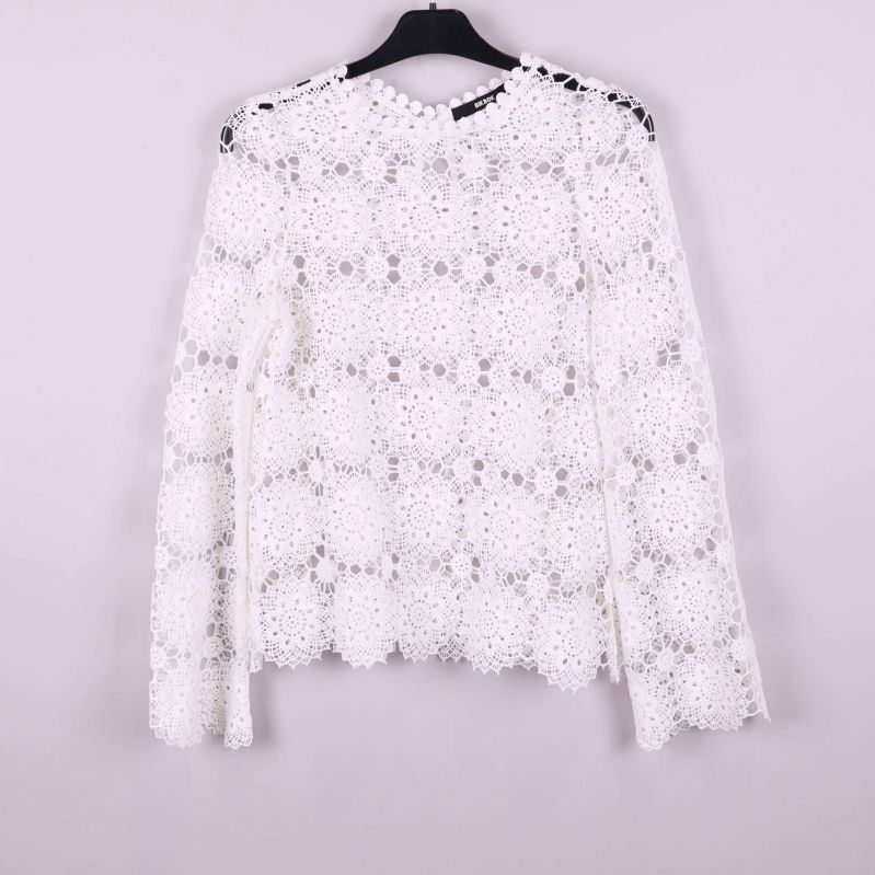 Baksidan av vit spetsblus med knappdetalj vid nacken
