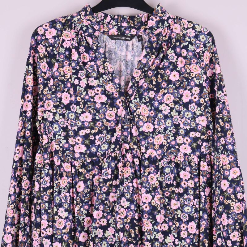 Detaljbild på övre delen av klänningens blommönster och öppning