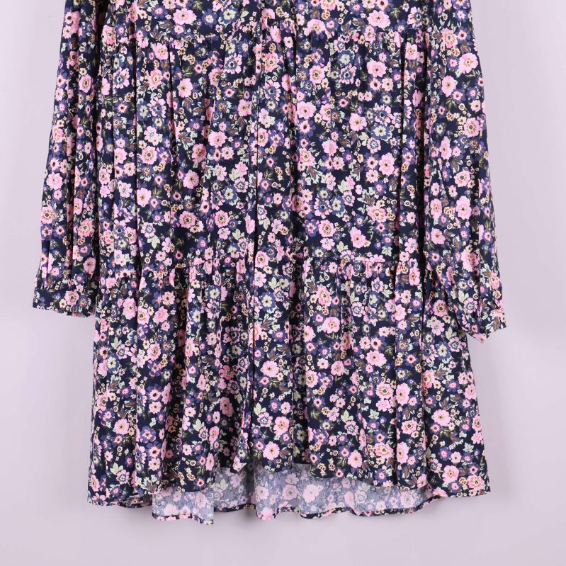 Närbild på blommiga volanger i nedre delen av klänningen