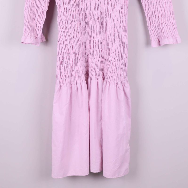 Närbild på nederdelen av ljusrosa smockad klänning