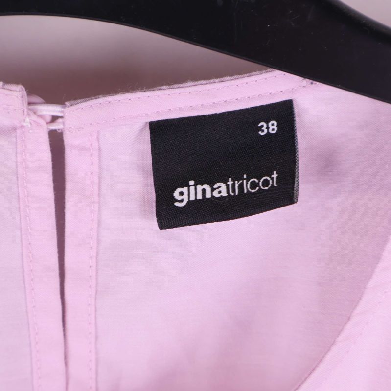 Närbild på märkeslapp ginatricot och storlek 38 i klänning