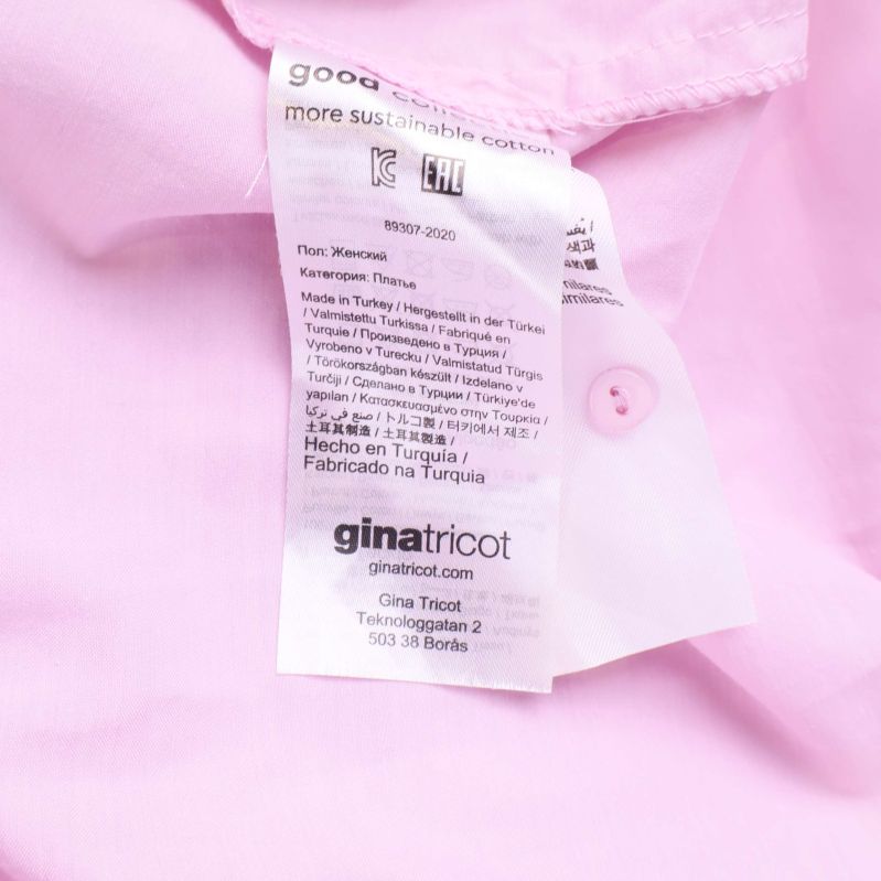 Materiallapp med information från ginatricot i ljusrosa klänning