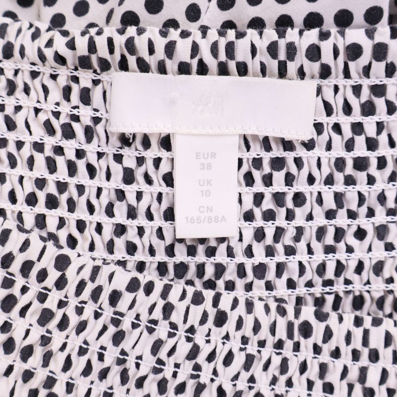 Etikett med storlek EUR 38 på klänning i prickigt tyg