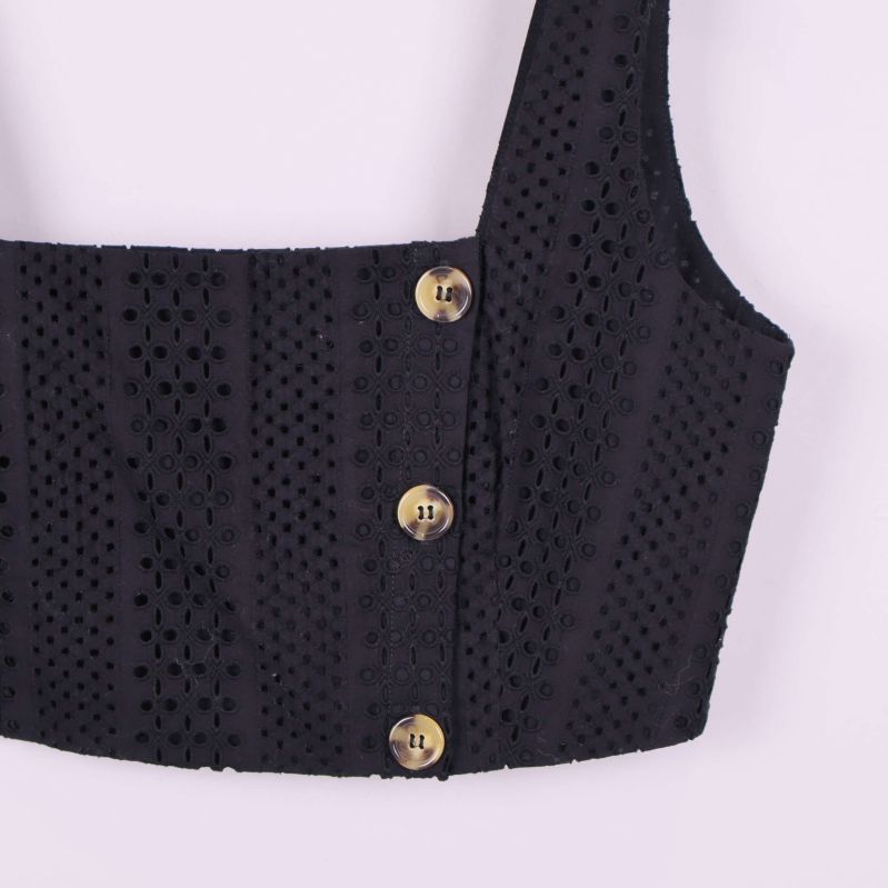 Närbild på tre guldfärgade knappar på svart topp