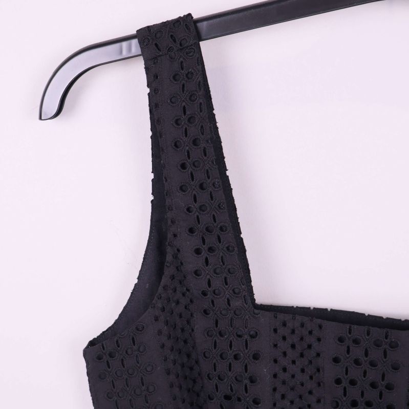 Närbild axelband och broderad struktur på svart topp