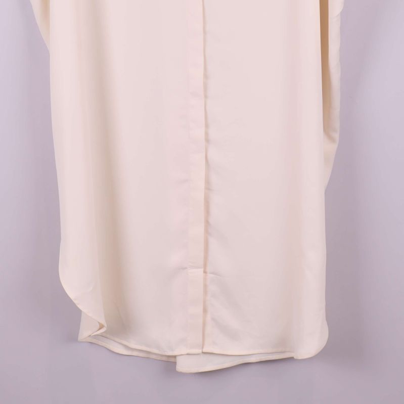 Detalj av nederkant på krämvit kaftan med rundad form