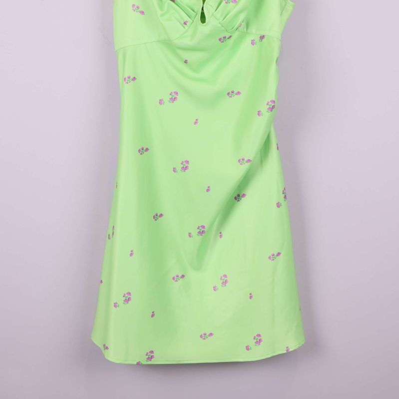 Nedre del av ljusgrön klänning med små lila blommor
