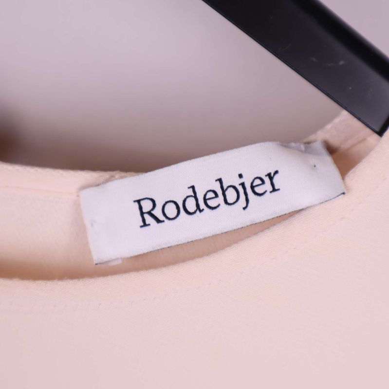 Närbild på vit etikett med Rodebjer logotyp i halsen