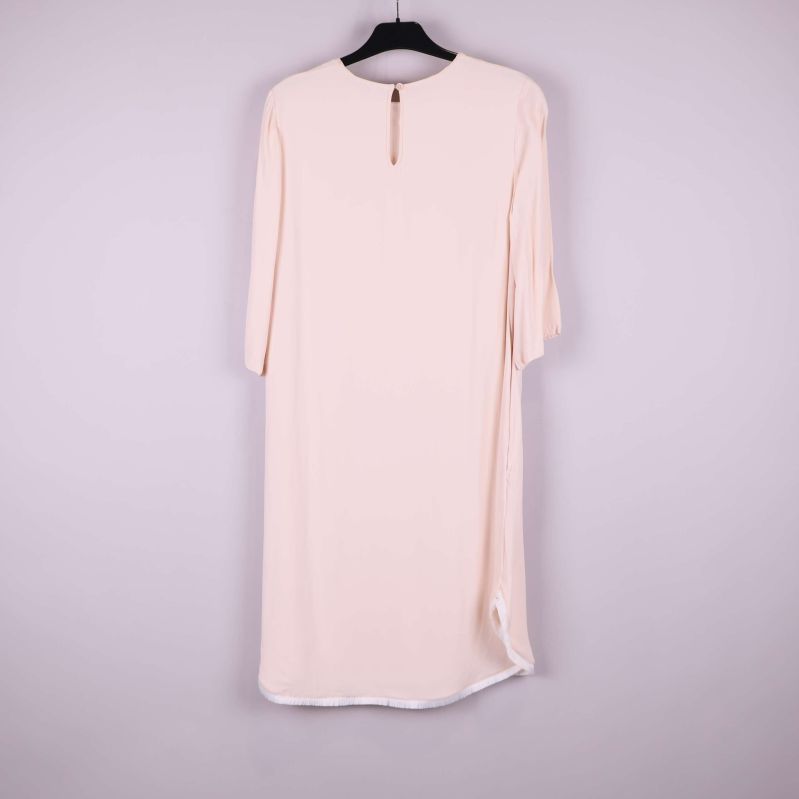 Baksidan av ljusbeige klänning med knapp i nacken