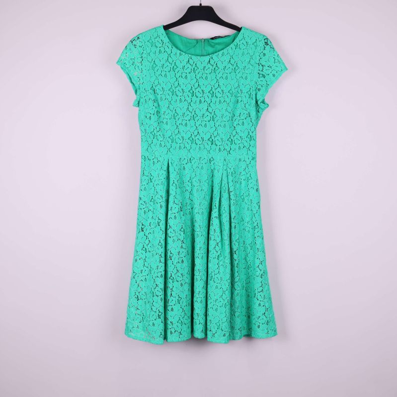 Grön spetsklänning med rund hals och korta ärmar hängande på galge, sedd framifrån